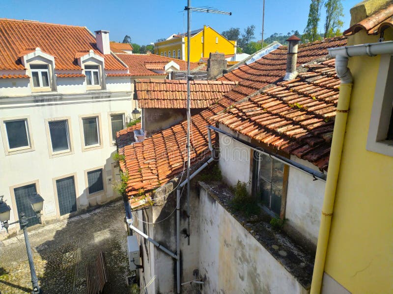 ALCOBACA PORTUGALIA KWIECIEŃ 24 2025 : Kaskada dachów z kafelkami w słonecznym widoku podświetlenia. Budynki pokazują wiek i archi obrazy stock