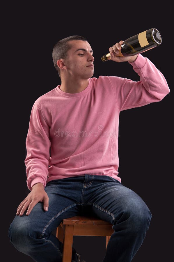 Alcohol de consumición del hombre joven en negro fotografía de archivo libre de regalías Alcohol de consumición del hombre joven en negro fotografía de archivo libre de regalías
