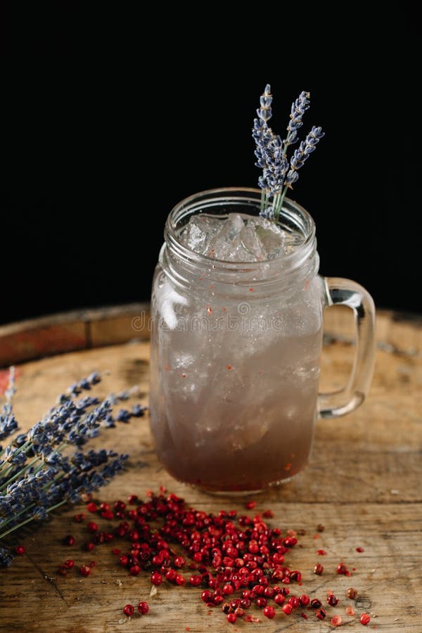 An alcoholic beverage garnished with lavender and peppercorns. An alcoholic beverage on dark background stock images An alcoholic beverage garnished with lavender and peppercorns. An alcoholic beverage on dark background stock images
