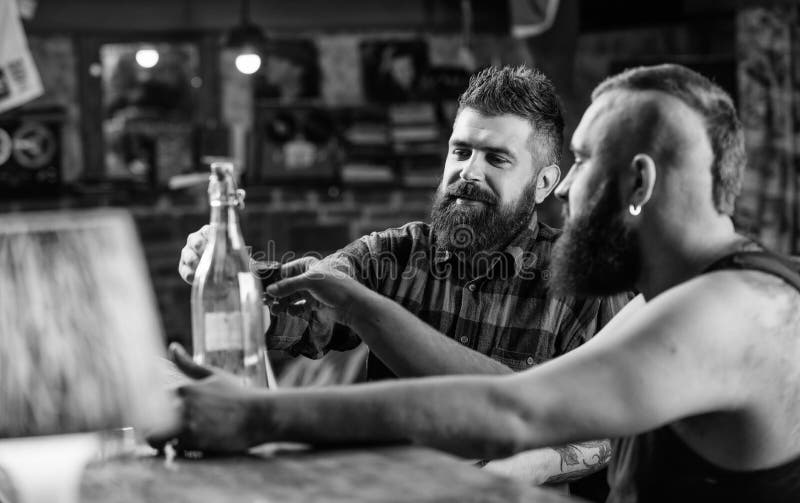 Alcool bevente dell'uomo brutale dei pantaloni a vita bassa con l'amico al contatore della barra Uomini che bevono insieme alcool fotografie stock Alcool bevente dell'uomo brutale dei pantaloni a vita bassa con l'amico al contatore della barra Uomini che bevono insieme alcool fotografie stock