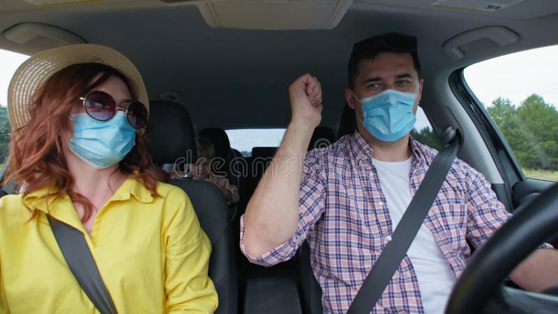 Alegre família feliz se divirta durante a viagem conjunta de carro nas férias observem precauções de segurança e usem máscaras méd