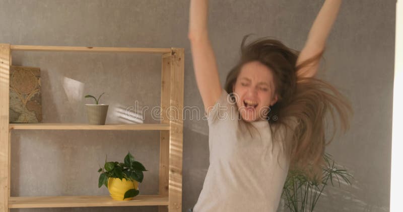 Alegre niña feliz ríe y salta. mujer joven bailando en la sala de estar. movimiento lento. luz del día almacen de video