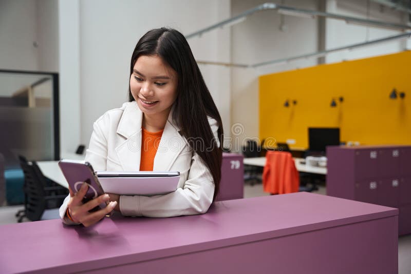 Alegre trabajador corporativo leyendo algo en el teléfono celular en la oficina abierta fotografía de archivo libre de regalías