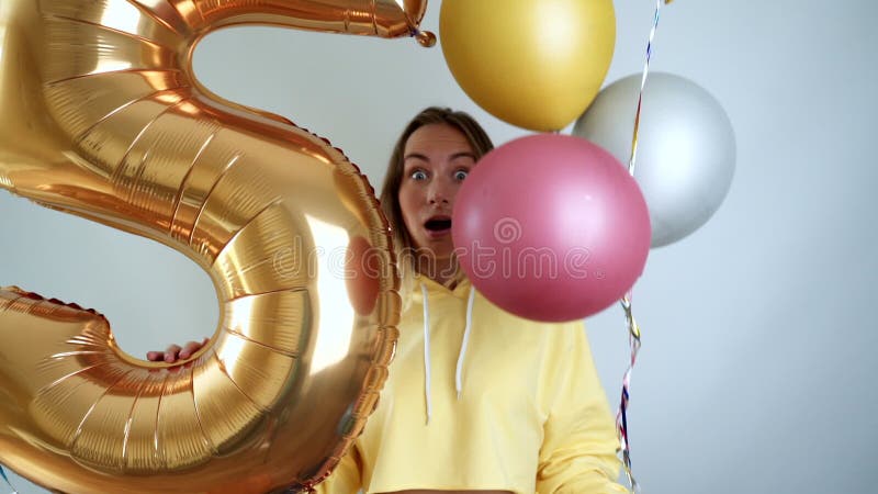 Alegre y enérgica mujer alegre que ríe y baila con coloridos globos de aire disfrutando de la fiesta de cumpleaños almacen de metraje de vídeo