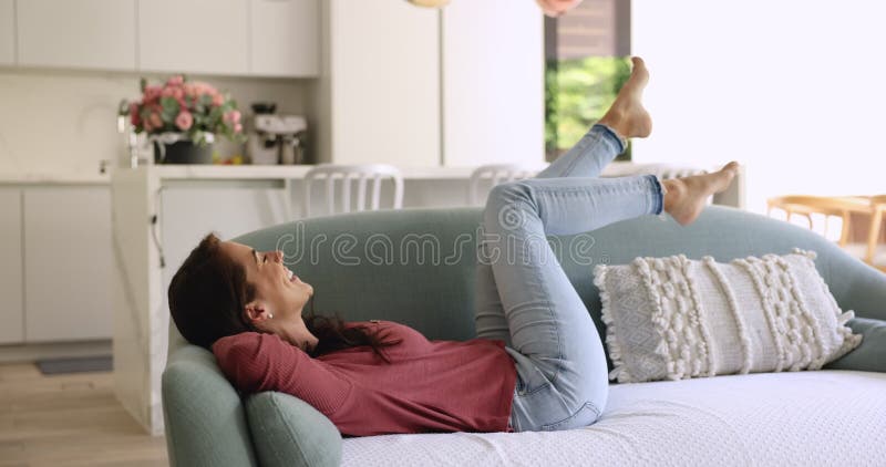 Alegre y feliz mujer latino propietaria tirada en el sofá metrajes