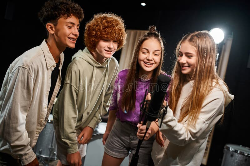 cheerful cute teenagers in everyday vibrant attires singing together into microphone, musical group, stock photo. cheerful cute teenagers in everyday vibrant attires singing together into microphone, musical group, stock photo