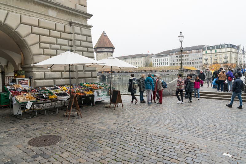 Alfalfa, LU/Suiza - 9 de noviembre de 2018: muchos peatones y transeúntes y gente ocupados que cruzan un puente y una plaza w fotos de archivo libres de regalías Alfalfa, LU/Suiza - 9 de noviembre de 2018: muchos peatones y transeúntes y gente ocupados que cruzan un puente y una plaza w fotos de archivo libres de regalías