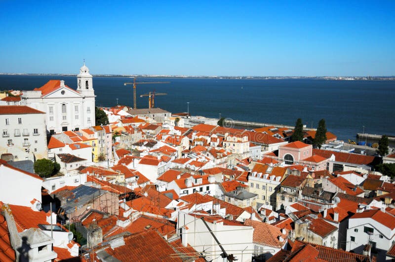 Aerial view of old buildings in Alfama quarter with ocean in background, Lisbon city, Portugal. Aerial view of old buildings in Alfama quarter with ocean in background, Lisbon city, Portugal.