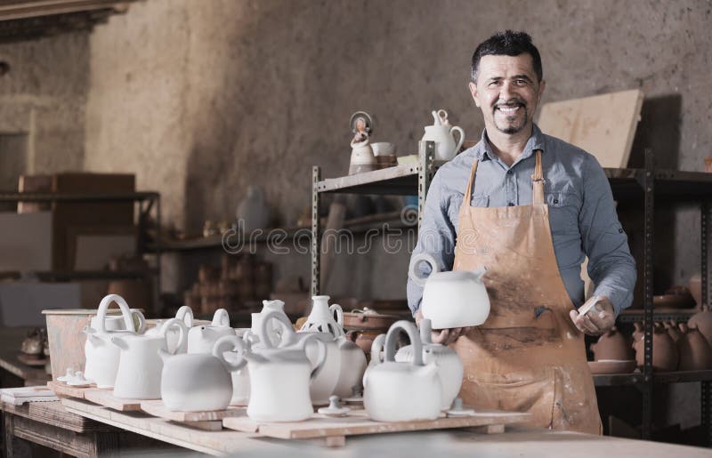 Alfarero del hombre que sostiene los buques de cerámica en taller imágenes de archivo libres de regalías Alfarero del hombre que sostiene los buques de cerámica en taller imágenes de archivo libres de regalías