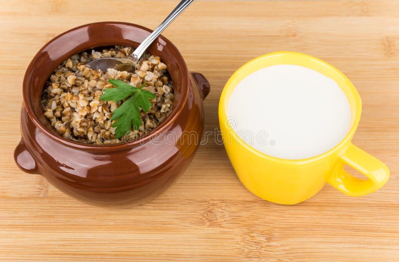 Alforfón cocinado en pote y la taza de cerámica marrones de leche imágenes de archivo libres de regalías Alforfón cocinado en pote y la taza de cerámica marrones de leche imágenes de archivo libres de regalías
