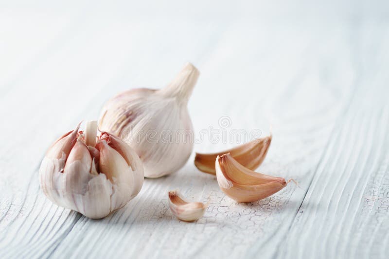 Alho e cravos-da-índia de alho na tabela de madeira branca imagem de stock Alho e cravos-da-índia de alho na tabela de madeira branca imagem de stock