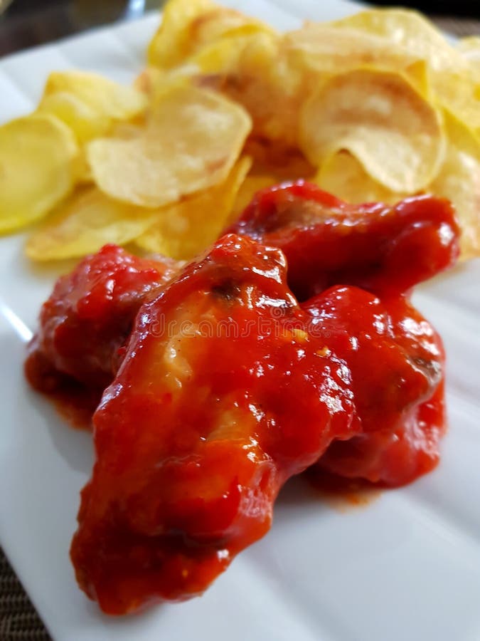 Ali di pollo con salsa piccante e le patate fritte fotografia stock Ali di pollo con salsa piccante e le patate fritte fotografia stock