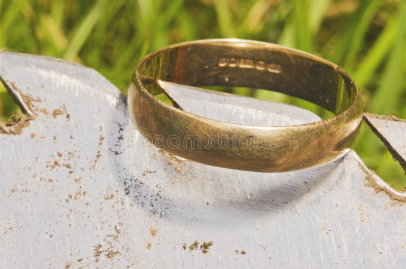 Aliança de casamento do ouro velho exposta na pá, encontrada na escavação da vida pelo detector de metais
