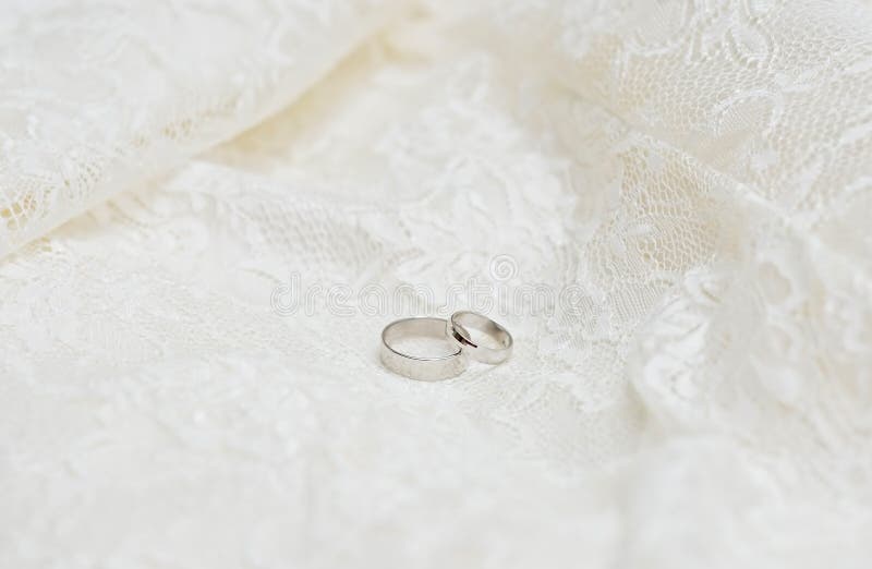 Alianças de casamento no fundo do laço imagens de stock Alianças de casamento no fundo do laço imagens de stock