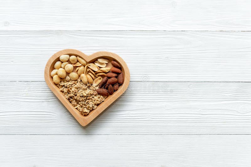 Alimenti sani Dadi misti nella forma del cuore con i dadi per la dieta su legno bianco Generi differenti di dadi saporiti e sani fotografia stock