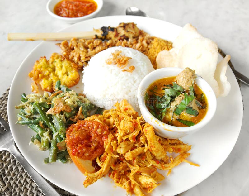 A traditional ethnic asian meal of Nasi Campur, or white rice served with assorted side dishes of various spicy meats and vegetables. Delicious and ethnic cuisine found in Indonesia and bali. Popular main course menu item in restaurant and cafe, both with locals and tourists. Beautiful professional foods photography with day lighting. A traditional ethnic asian meal of Nasi Campur, or white rice served with assorted side dishes of various spicy meats and vegetables. Delicious and ethnic cuisine found in Indonesia and bali. Popular main course menu item in restaurant and cafe, both with locals and tourists. Beautiful professional foods photography with day lighting.