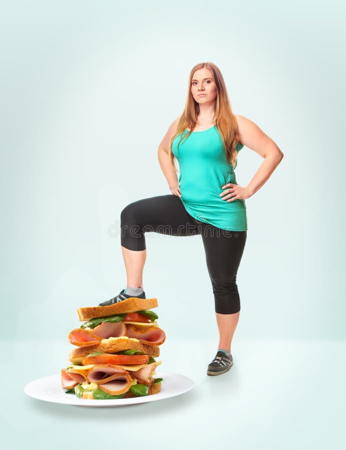 A fat woman steps on the burger. Unhealthy food. The concept of dieting and healthy lifestyle for fat woman. A fat woman steps on the burger. Unhealthy food. The concept of dieting and healthy lifestyle for fat woman
