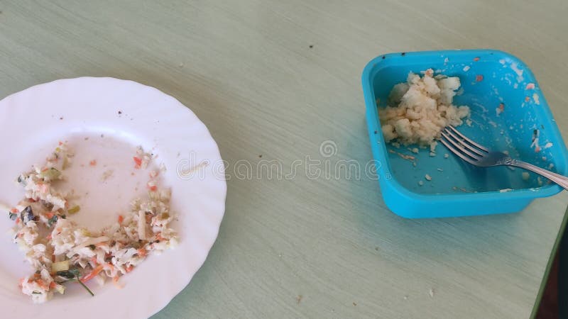 Alimento remanescente num recipiente e placa sobre a mesa