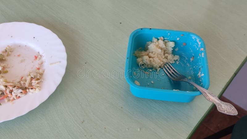 Alimento remanescente num recipiente e placa sobre a mesa