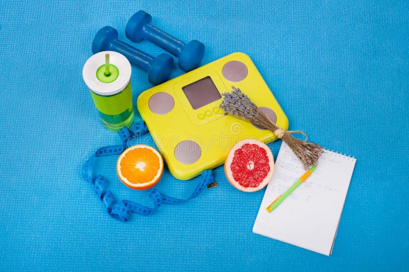 Alimentos saludables, básculas y accesorios deportivos en un fondo azul imagen de archivo libre de regalías