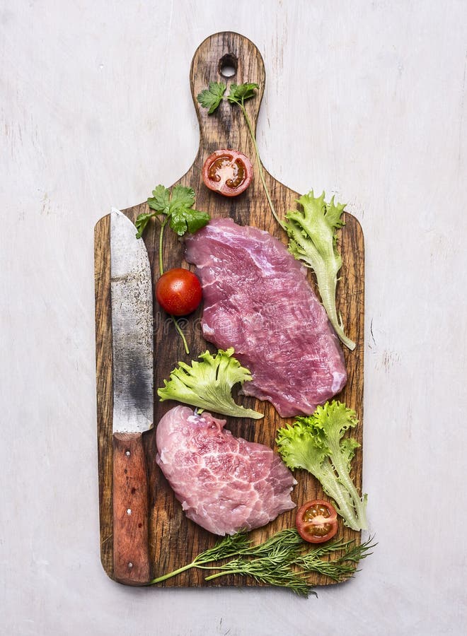 Alimentos saudáveis, cozinhando o bife fresco da carne de porco do conceito com salada, tomate com uma faca para a placa de corte foto de stock royalty free Alimentos saudáveis, cozinhando o bife fresco da carne de porco do conceito com salada, tomate com uma faca para a placa de corte foto de stock royalty free