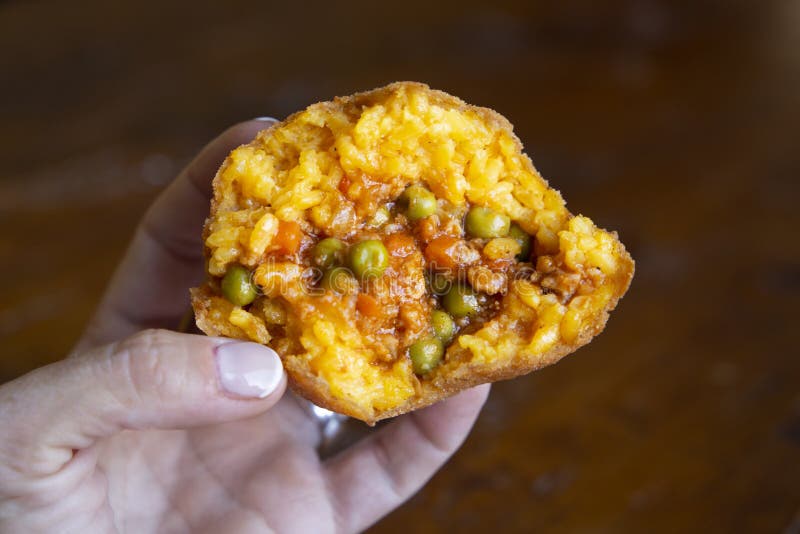 View of the interior of a meat arancino and peas. Orange rice is seen due to the saffron surrounding stewed meat and peas. On the outside of the arancino you can see the characteristic crispy frying of this dish. View of the interior of a meat arancino and peas. Orange rice is seen due to the saffron surrounding stewed meat and peas. On the outside of the arancino you can see the characteristic crispy frying of this dish