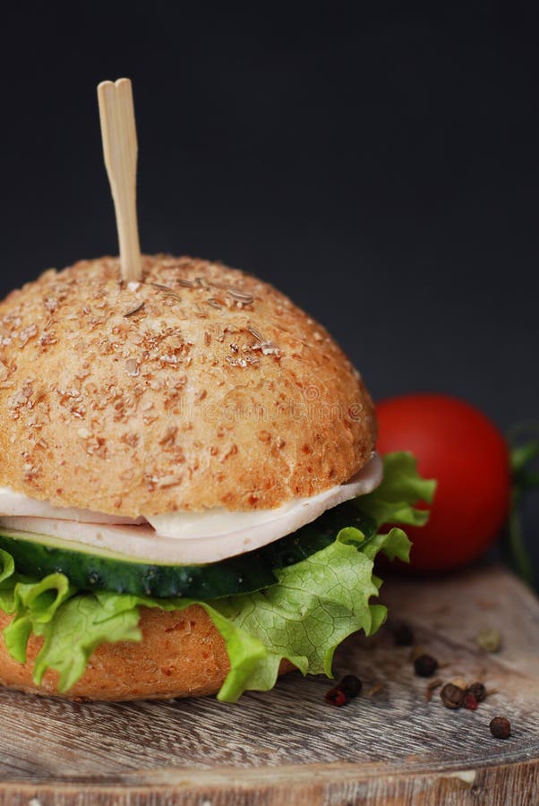 Aliments de préparation rapide, hamburger fait maison avec des tomates sur un Tableau en bois et fond noir Image verticale photographie stock Aliments de préparation rapide, hamburger fait maison avec des tomates sur un Tableau en bois et fond noir Image verticale photographie stock