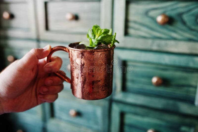 Alkoholiserad coctail med is, mintkaramellen och limefrukt i bronskopp på handen royaltyfria foton Alkoholiserad coctail med is, mintkaramellen och limefrukt i bronskopp på handen royaltyfria foton