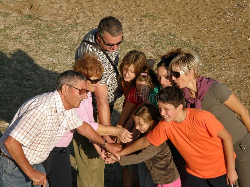 Primo piano ritratto di una grande famiglia sorridente (nonni e nipoti di tre diverse generazioni della stessa famiglia) dei popoli mani insieme (prendere con le mani giunte) alla spiaggia di sabbia.