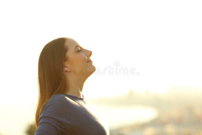 Side view portrait of a single woman breathing deeply fresh air at sunset. Side view portrait of a single woman breathing deeply fresh air at sunset