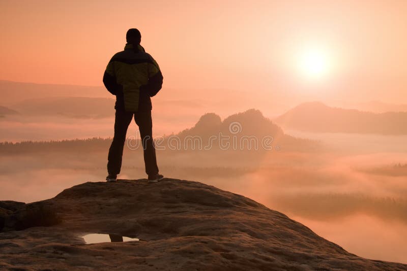 Hiker standing on top of a mountain and enjoying sunrise. Hiker standing on top of a mountain and enjoying sunrise