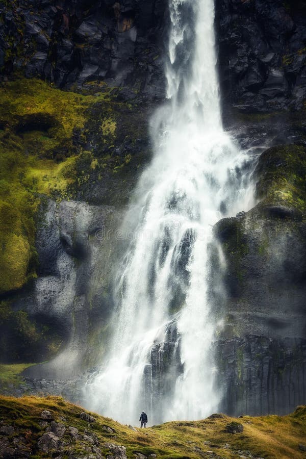 Alleinwanderung vor einem gewaltigen Wasserfall im Eisland lizenzfreie stockfotografie