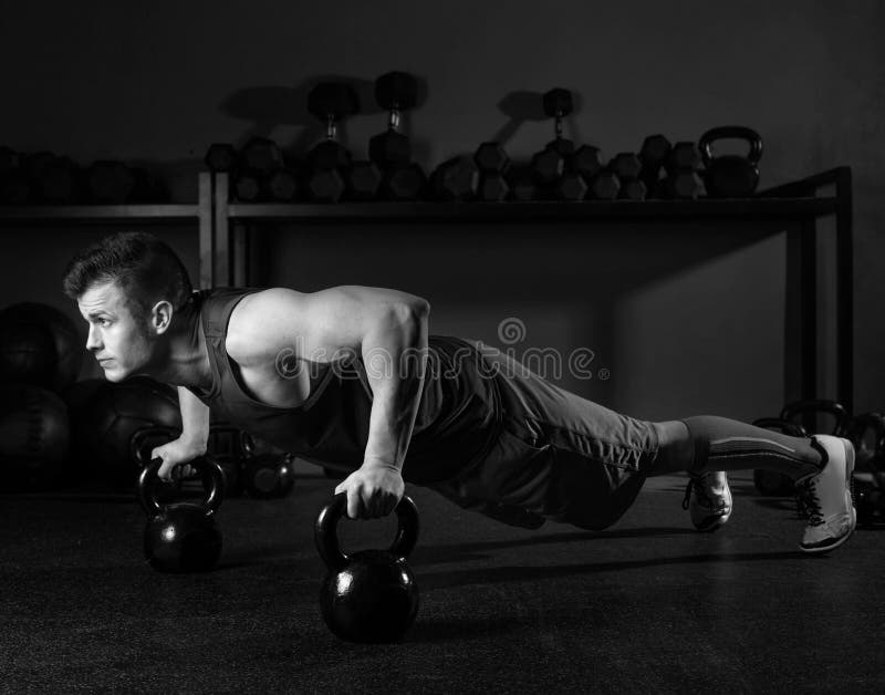 Allenamento della palestra di forza dell'uomo di flessione di Kettlebells fotografie stock Allenamento della palestra di forza dell'uomo di flessione di Kettlebells fotografie stock