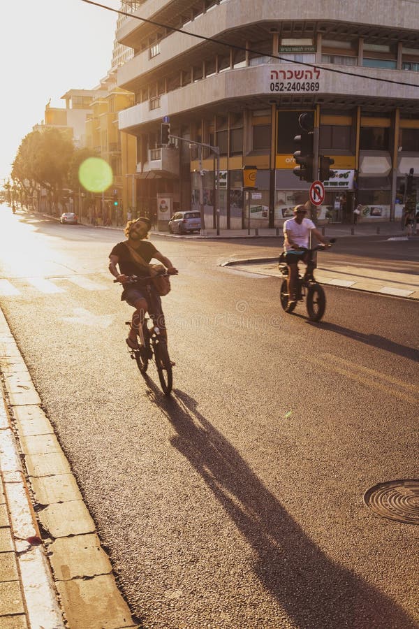 Tel Aviv-Yafo, Israel - June 6, 2018: Sunset scene with bike riders at Allenby Road in Tel Aviv, Israel. Bikes are the most popular transportation in Tel Aviv. Tel Aviv-Yafo, Israel - June 6, 2018: Sunset scene with bike riders at Allenby Road in Tel Aviv, Israel. Bikes are the most popular transportation in Tel Aviv.