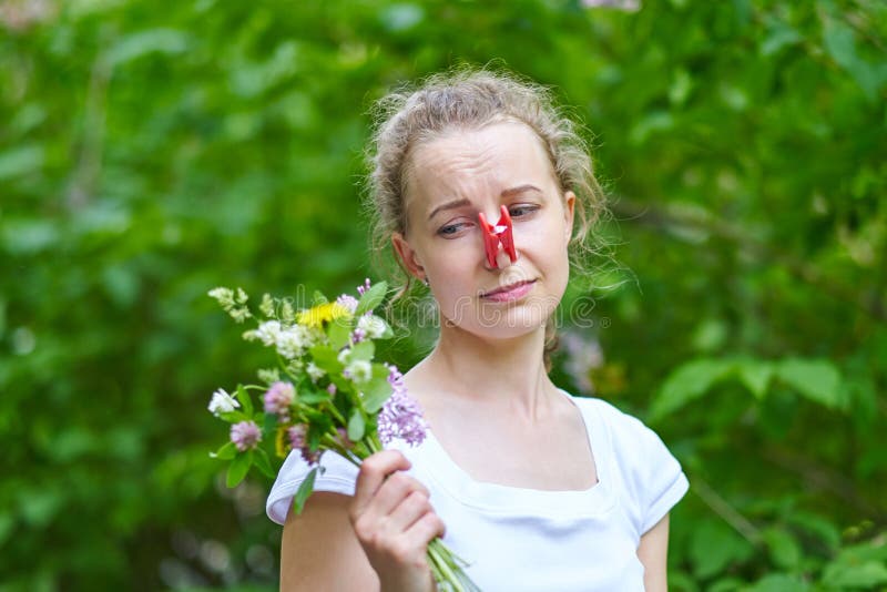 allergie De vrouw drukte haar neus met een wasknijper, zodat zo om van het stuifmeel van bloemen te niezen niet