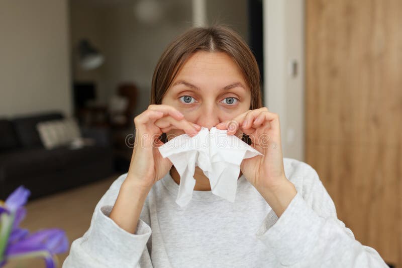 Allergy, flu, cold, rhinitis. Funny face of sick woman with paper tissues inside nose from runny nose and sneezes at home. Hay fever, sinusitis and female with viral infection blowing in handkerchief. Allergy, flu, cold, rhinitis. Funny face of sick woman with paper tissues inside nose from runny nose and sneezes at home. Hay fever, sinusitis and female with viral infection blowing in handkerchief.