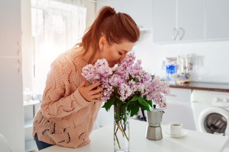 Allergy free. Happy woman smelling lilac in modern kitchen. Seasonal allergy concept. stock photos Allergy free. Happy woman smelling lilac in modern kitchen. Seasonal allergy concept. stock photos