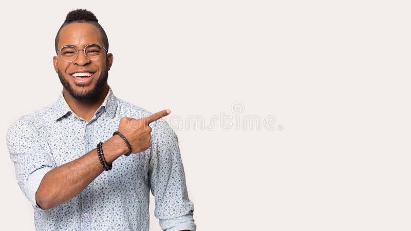 Happy african American man in glasses and shirt point with finger at blank copy space aside, smiling black male in spectacles isolated on grey background show free advertising place or sale offer. Happy african American man in glasses and shirt point with finger at blank copy space aside, smiling black male in spectacles isolated on grey background show free advertising place or sale offer