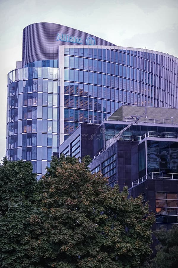 Allianz skyskrapa med glasfasad. Nordlig, modern skyskrapa med allianz-logotyp omgiven av träd.