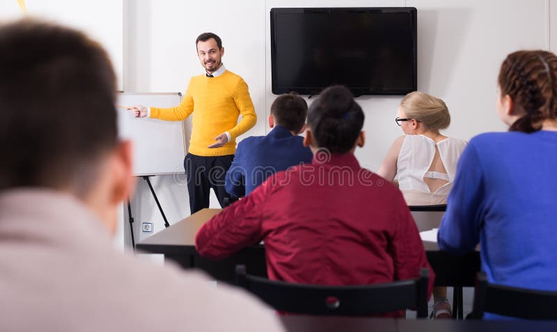 Allievi che ascoltano con le spiegazioni dei teacher’s di interesse immagini stock Allievi che ascoltano con le spiegazioni dei teacher’s di interesse immagini stock