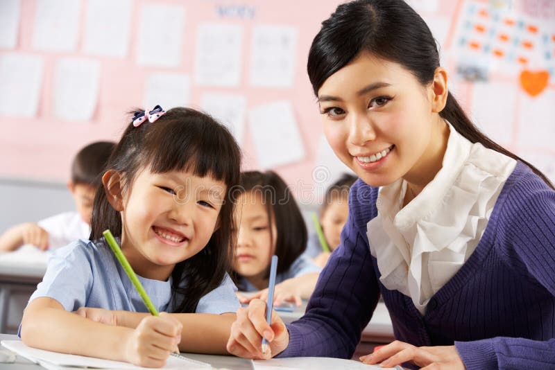 Allievo d'aiuto funzionare allo scrittorio a scuola cinese immagine stock Allievo d'aiuto funzionare allo scrittorio a scuola cinese immagine stock