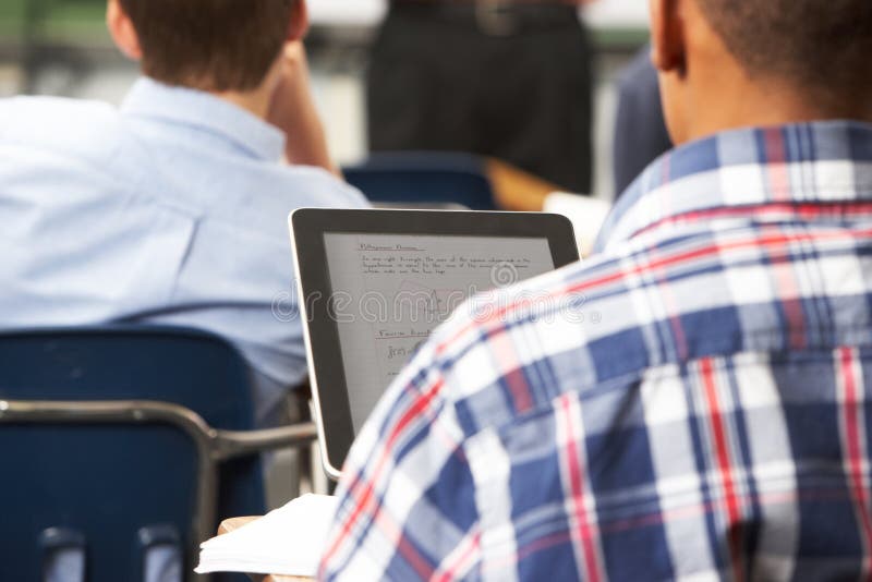 Allievo maschio che utilizza la compressa di Digital nell'aula immagini stock Allievo maschio che utilizza la compressa di Digital nell'aula immagini stock