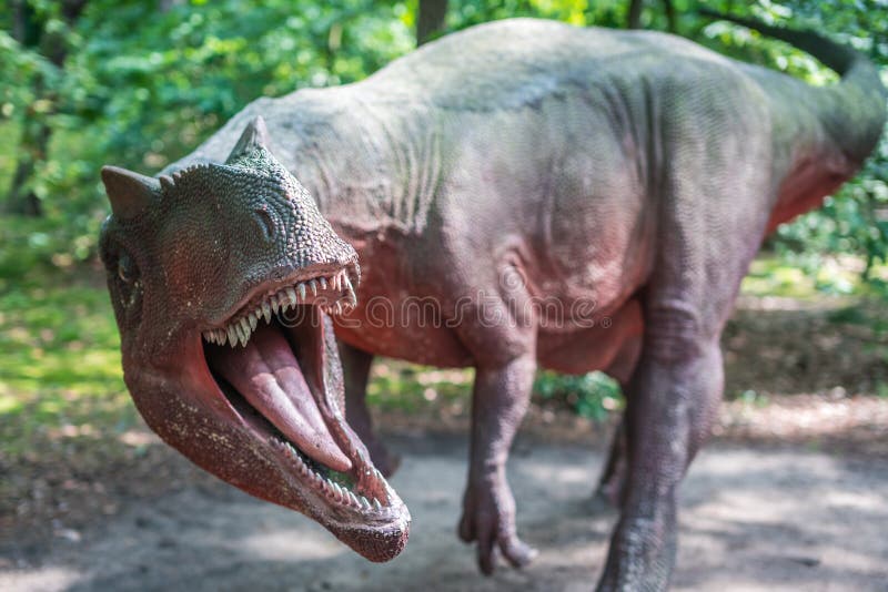 Life sized Allosaurus dinosaur statue in a forest