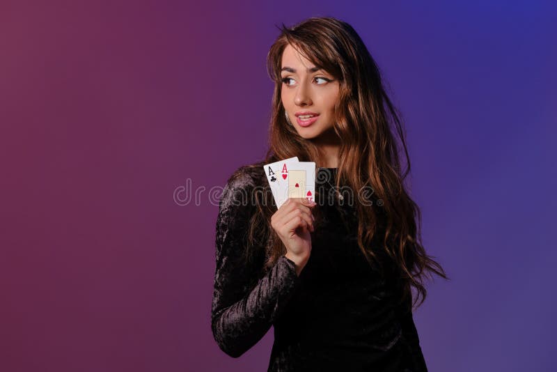 Brunette woman in black velvet dress showing two playing cards, posing against coloful background. Gambling