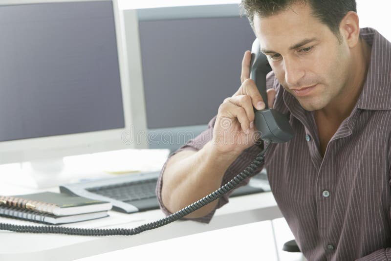 Allvarlig affärsman Using Landline Phone på skrivbordet arkivbild