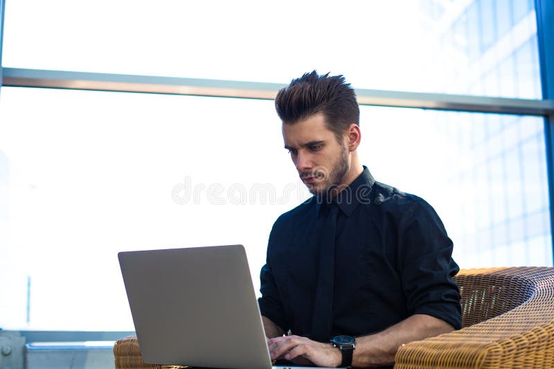 Allvarlig manlig entreprenör som arbetar på webbsidan via anteckningsboken Framstickandeonline-bokning arkivfoto Allvarlig manlig entreprenör som arbetar på webbsidan via anteckningsboken Framstickandeonline-bokning arkivfoto