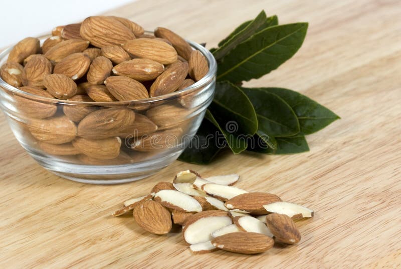 Fresh raw almonds in glass bowl on wood cutting board. Fresh raw almonds in glass bowl on wood cutting board