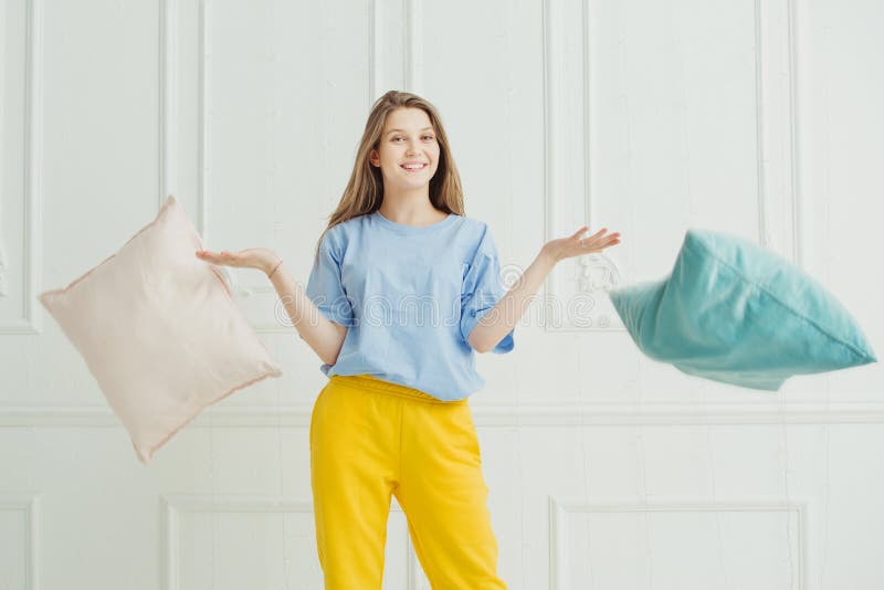 Almohadas que lanzan sonrientes de la muchacha Mujer juguetona feliz en pijama fotos de archivo libres de regalías Almohadas que lanzan sonrientes de la muchacha Mujer juguetona feliz en pijama fotos de archivo libres de regalías