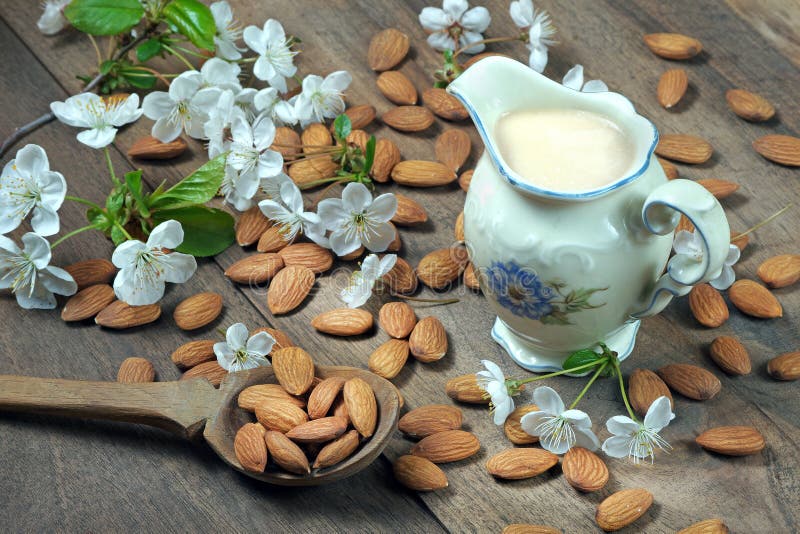 Almond milk in a jar, almonds on the table and white spring flowers. royalty free stock image