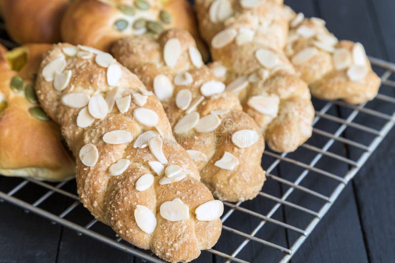 Almond twist bread on oven grill on black wooden table. Fresh almond twist breads on oven grill on black wooden table stock photos Almond twist bread on oven grill on black wooden table. Fresh almond twist breads on oven grill on black wooden table stock photos